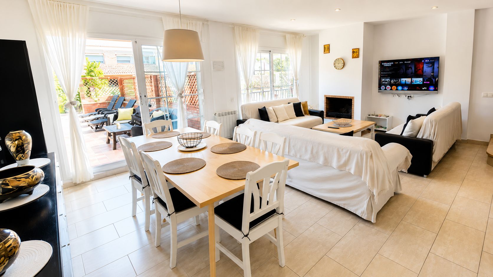 Una sala de estar moderna con comedor, chimenea y televisor montado en la pared.