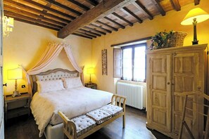 A bedroom with a four-poster bed, a wooden cabinet, and a window with curtains. - Tuscan casale with hot tub, pool and valley views (Sillico)