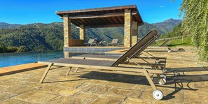 A poolside area with lounge chairs, a pergola, and a view of a mountainous landscape. - Tuscan casale with hot tub, pool and valley views (Sillico)
