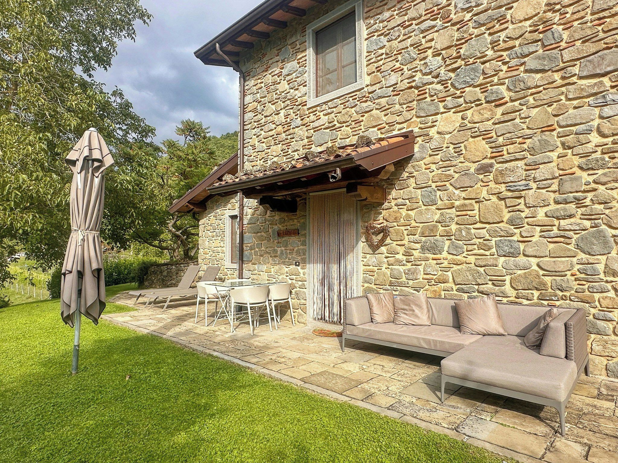 Une maison en pierre dotée d’un patio, de mobilier d’extérieur et d’un espace salon abrité.