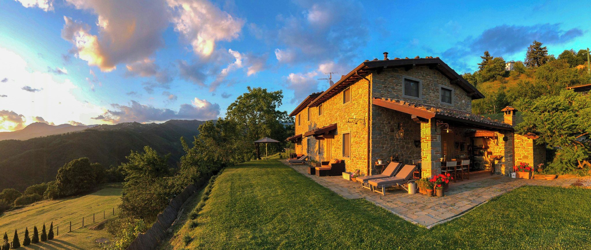 Une maison en pierre dotée d’une terrasse, d’un espace salon extérieur et offrant une vue sur le paysage environnant.