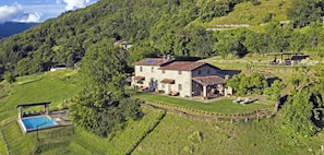 A stone house with a swimming pool, surrounded by lush greenery and hills. - Apartment in Tuscan farmhouse with pool and views (Sillico)