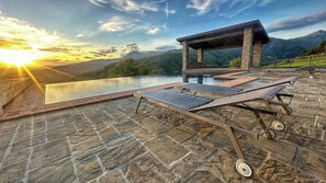 A stone patio with a pool, lounge chairs, and a pergola overlooking a mountainous landscape. - Apartment in Tuscan farmhouse with pool and views (Sillico)