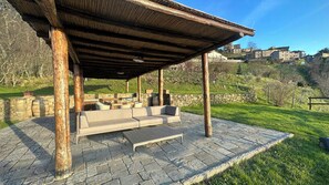 A covered outdoor seating area with stone flooring and a stone wall backdrop. - Apartment in Tuscan farmhouse with pool and views (Sillico)
