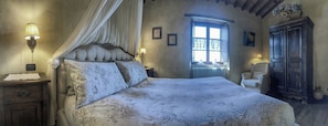 A bedroom with a large bed, a nightstand, a chair, a window, and a cabinet. - Apartment with Jacuzzi and pool on Tuscan hilltop (Sillico)