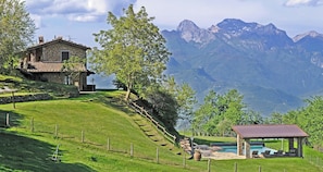A stone house with a terrace, a pool area with lounge chairs, and a view of mountains. - Apartment with Jacuzzi and pool on Tuscan hilltop (Sillico)