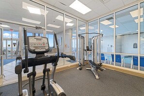 A gym with cardio equipment, weight machines, and a bench. - Admirals Quarters 304 by Liquid Life (Orange Beach)