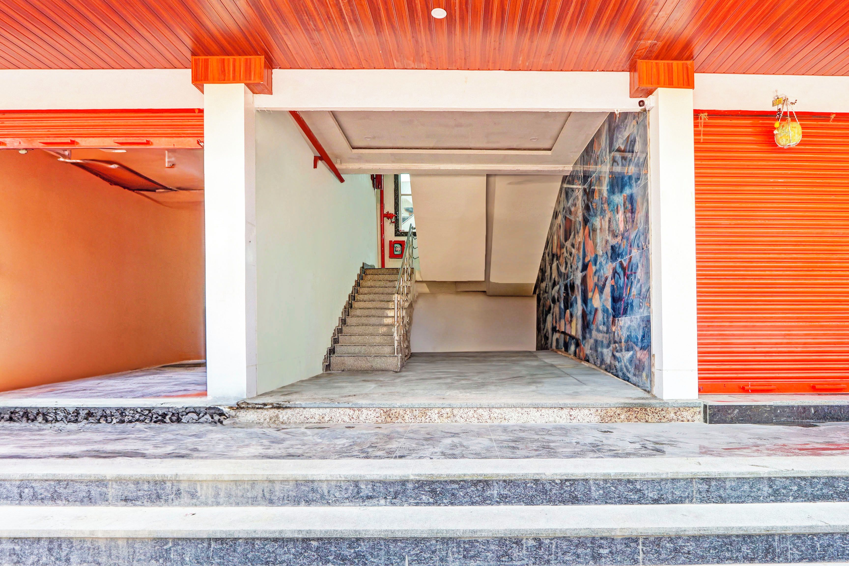 A hallway with a staircase leading to a landing, a fire extinguisher, and a red shutter door.