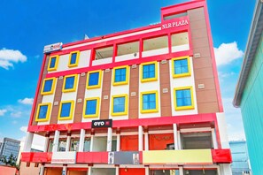A multi-story hotel with a red and yellow facade, multiple windows, and a sign for 'NLR PLAZA'.