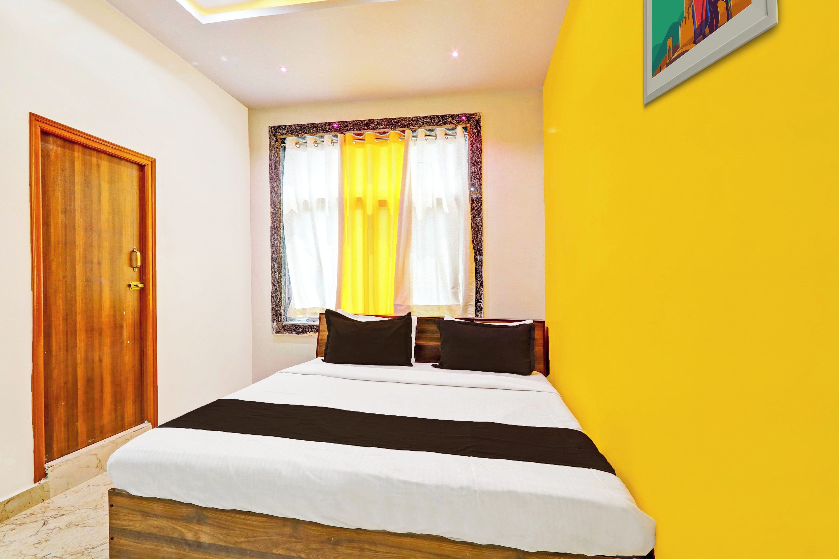 Una habitación de hotel con una cama, una puerta de madera y una ventana con cortinas.