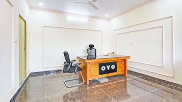 A conference room with a wooden desk, a black office chair, a ceiling fan, and a tiled floor.