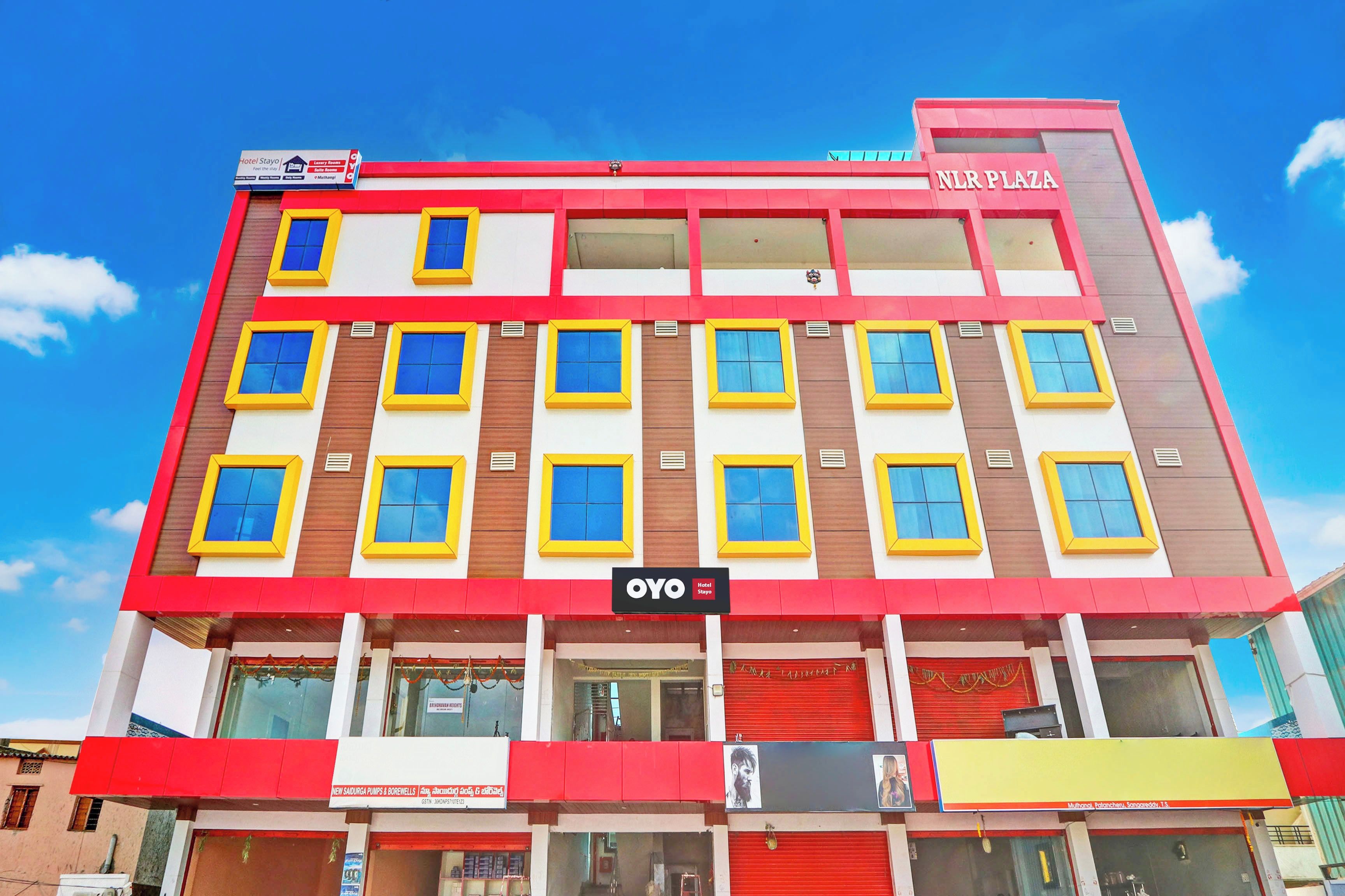 Een meerlaags hotelgebouw met een bord waarop 'Hotel Stayo' en 'NLR Plaza' staat.