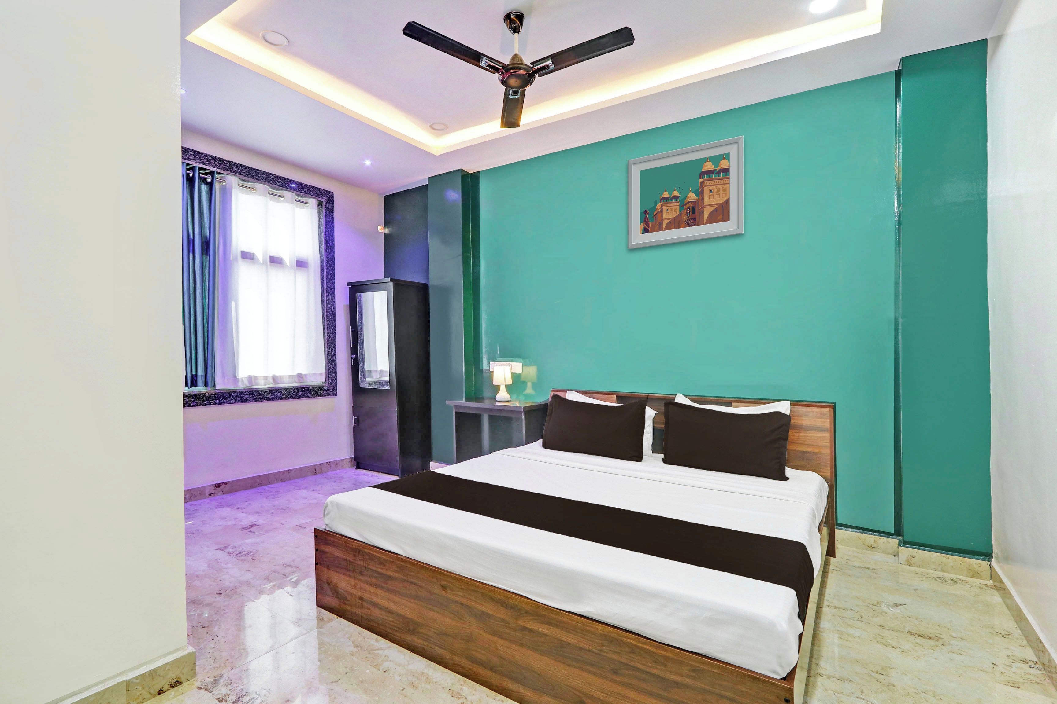 Quarto com cama, ventilador de teto, janela com cortinas e quadro pendurado na parede.