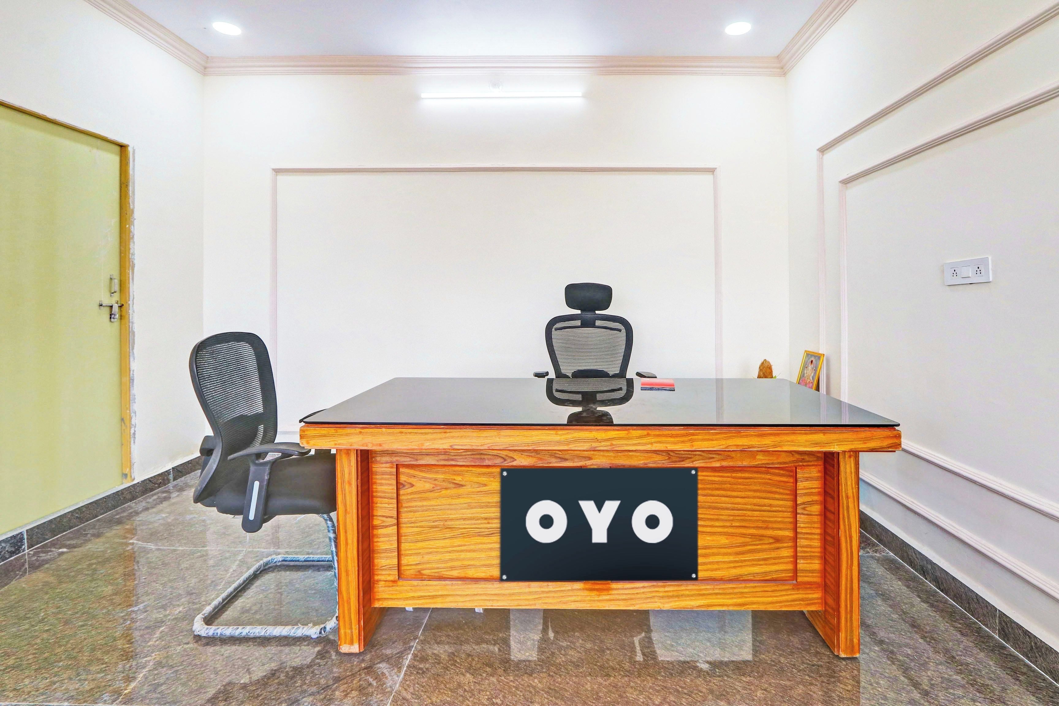 Een vergaderruimte met een houten tafel, een zwarte kantoorstoel en een bordje op tafel met de tekst 'OYO'.