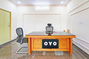 A conference room with a wooden table, a black office chair, and a sign on the table that reads 'OYO'.