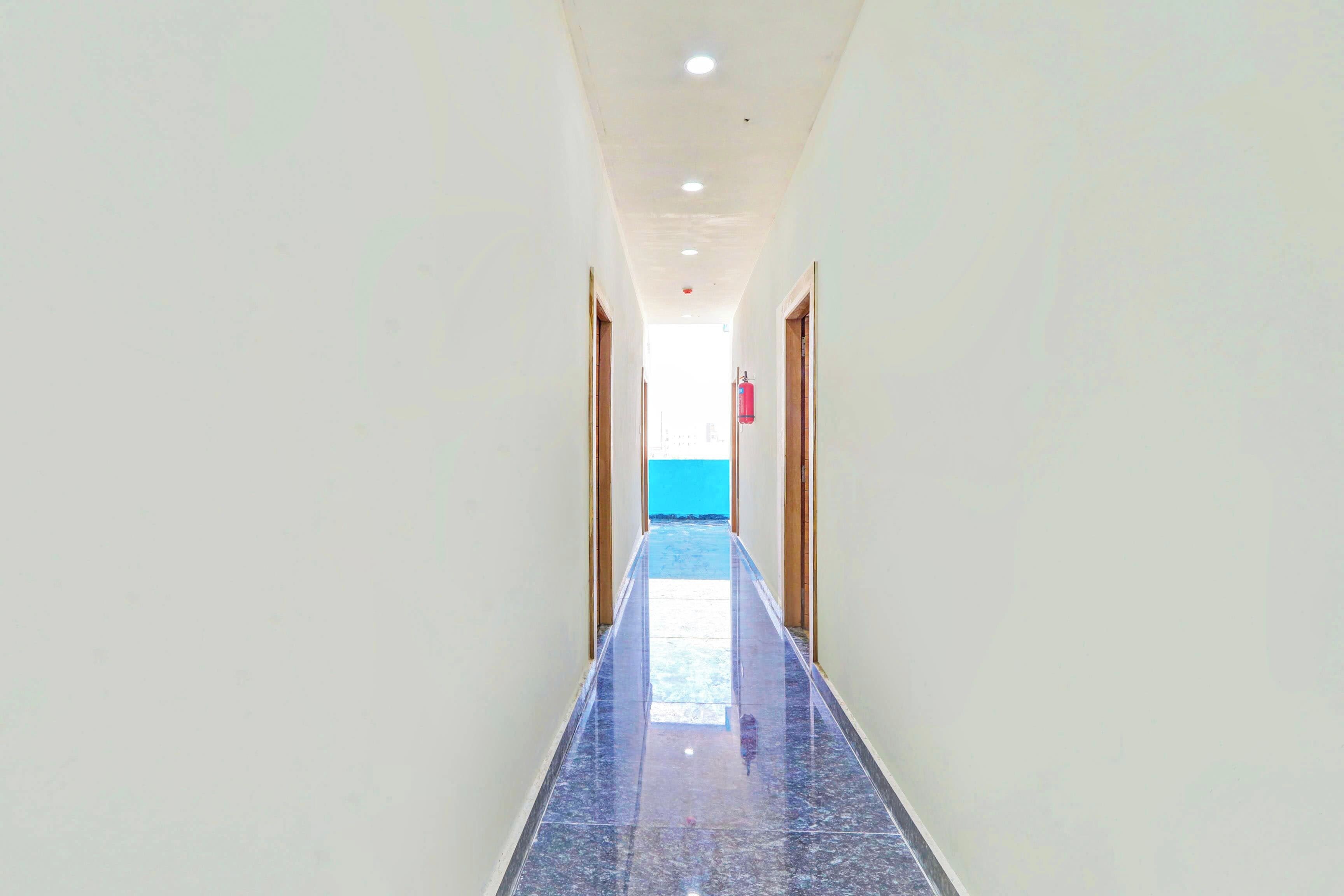 Um corredor com piso de azulejos brilhantes que leva a uma porta, com uma parede azul ao fundo.