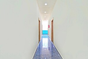 A corridor with a shiny tiled floor leading to a door with a blue wall in the background.