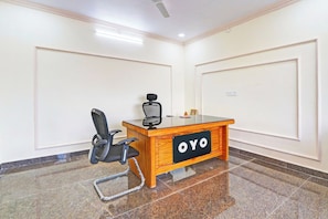 Un salón de conferencias con un escritorio de madera, una silla de oficina negra y un letrero que dice 'OYO'.