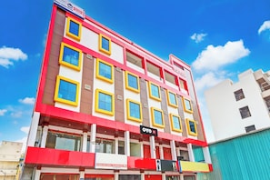 A multi-story hotel with a red and yellow facade, multiple windows, and a sign for 'OYO Hotel'.