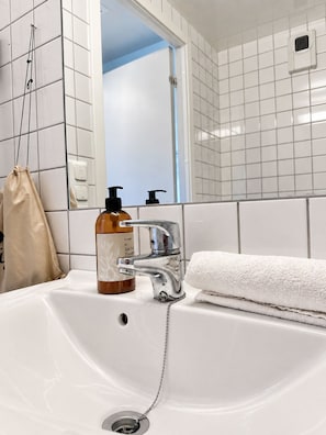 A bathroom with a white sink, a mirror, and a towel. - Modern Top-Floor Apartment with Balcony & City Views – All-Inclusive (Oslo)