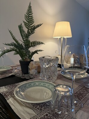 A dining table set with plates, a glass, a candle holder, and a potted fern. - Modern Top-Floor Apartment with Balcony & City Views – All-Inclusive (Oslo)