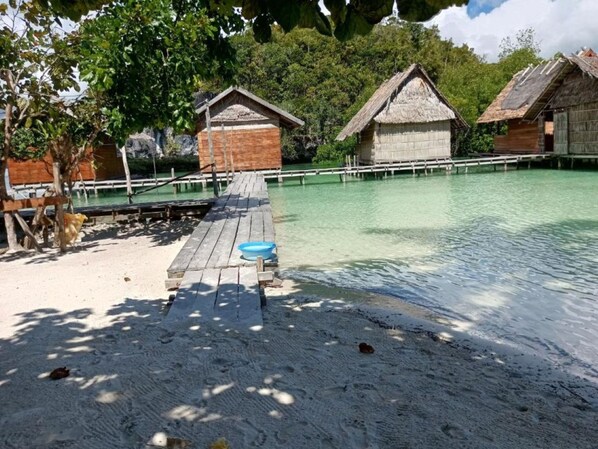 A wooden dock leading to overwater bungalows with clear turquoise water.