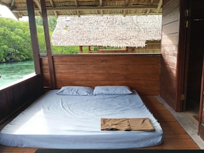Un lit simple avec un matelas et des oreillers, des murs en bois et une structure de toit en chaume.