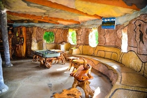 A room with a foosball table, a sofa, and a wooden table. - Lake Elementaita Nature Pebbles  (Gilgil)