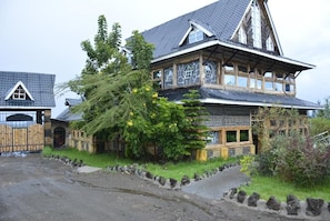 A traditional wooden house with a steeply pitched roof, large windows, and a stone foundation. - Lake Elementaita Nature Pebbles  (Gilgil)