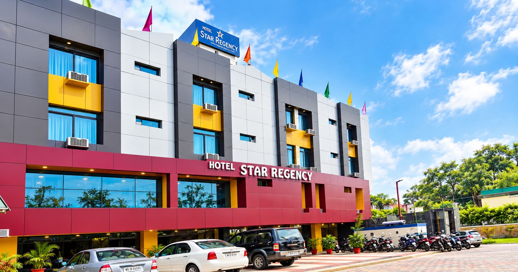 Un hotel de varios pisos con un llamativo letrero 'HOTEL STAR REGENCY', amplias ventanas y un estacionamiento con varios vehículos.