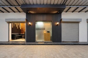 A modern building entrance with a glass door, a wooden slatted wall, and a metal shutter on the right. - Collection O Sector 10 Greater Noida (Noida)