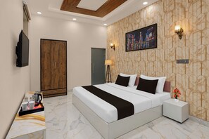 A modern bedroom with a large bed, a wooden wardrobe, a flat-screen TV, and a painting on the wall. - Collection O Sector 10 Greater Noida (Noida)