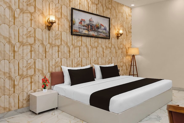 A hotel room with a bed, nightstand, lamp, and a painting on the wall. - Collection O Sector 10 Greater Noida (Noida)