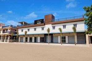 A multi-story building with a flat roof, a signboard, and a series of closed shutters on the ground floor. - Collection O Sector 10 Greater Noida (Noida)