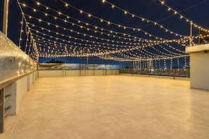 An outdoor terrace with string lights, a view of the cityscape, and a clear sky. - Collection O Sector 10 Greater Noida (Noida)