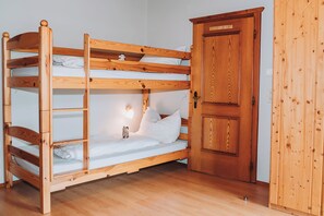 Ein Etagenbett mit einer Leiter, ein Nachttisch mit Lampe und ein Holzschrank.