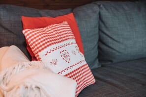 A grey sofa with a red and white checkered pillow and a white throw blanket. - 100 m² family apartment with south-facing balcony for up to 8 guests (Sankt Michael im Lungau)