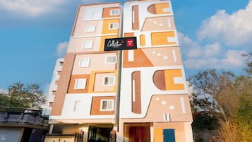 Un hotel de varios pisos con un diseño arquitectónico moderno, que presenta un letrero llamativo con el nombre y el logotipo del hotel.