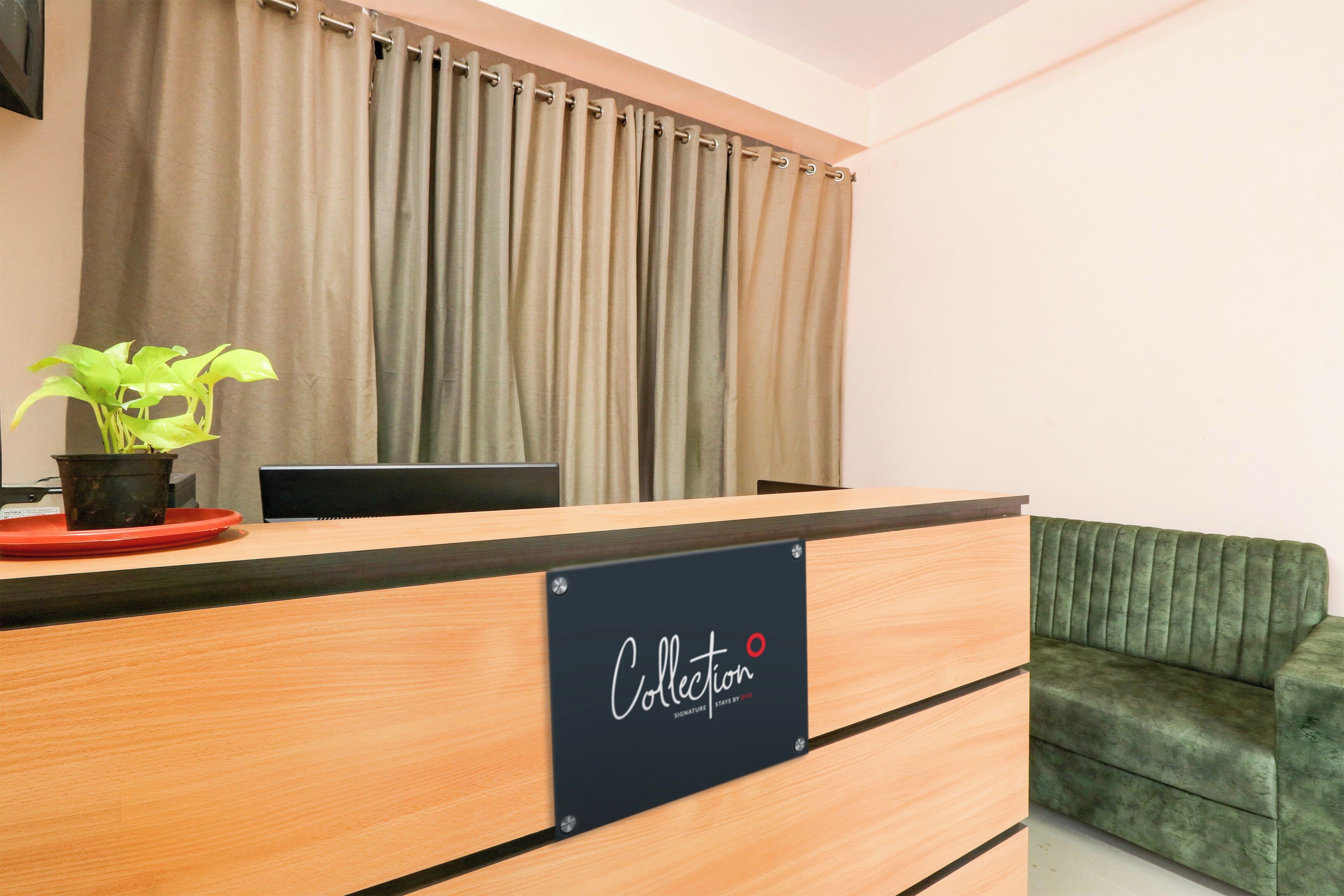 Un mostrador de recepción con un letrero que dice 'Collection Signature' y un sofá verde a la derecha.