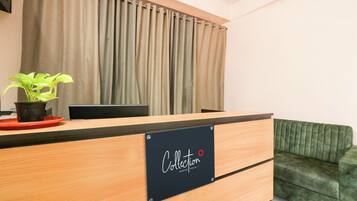 Un mostrador de recepción con un letrero que dice 'Collection Signature' y un sofá verde a la derecha.