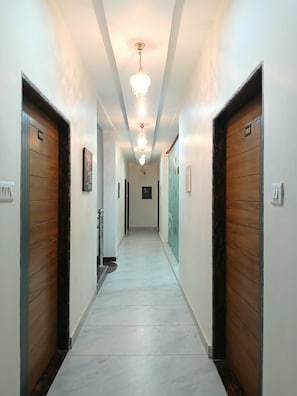 A hotel hallway with wooden doors numbered 101 and 102, a chandelier, and a tiled floor. - Kashi Prabha Homestay (Varanasi)