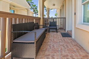 A covered outdoor seating area with wicker furniture and a tiled floor. - Cozy 2BR Condo w/shared POOL & Close to Beach! (South Padre Island)