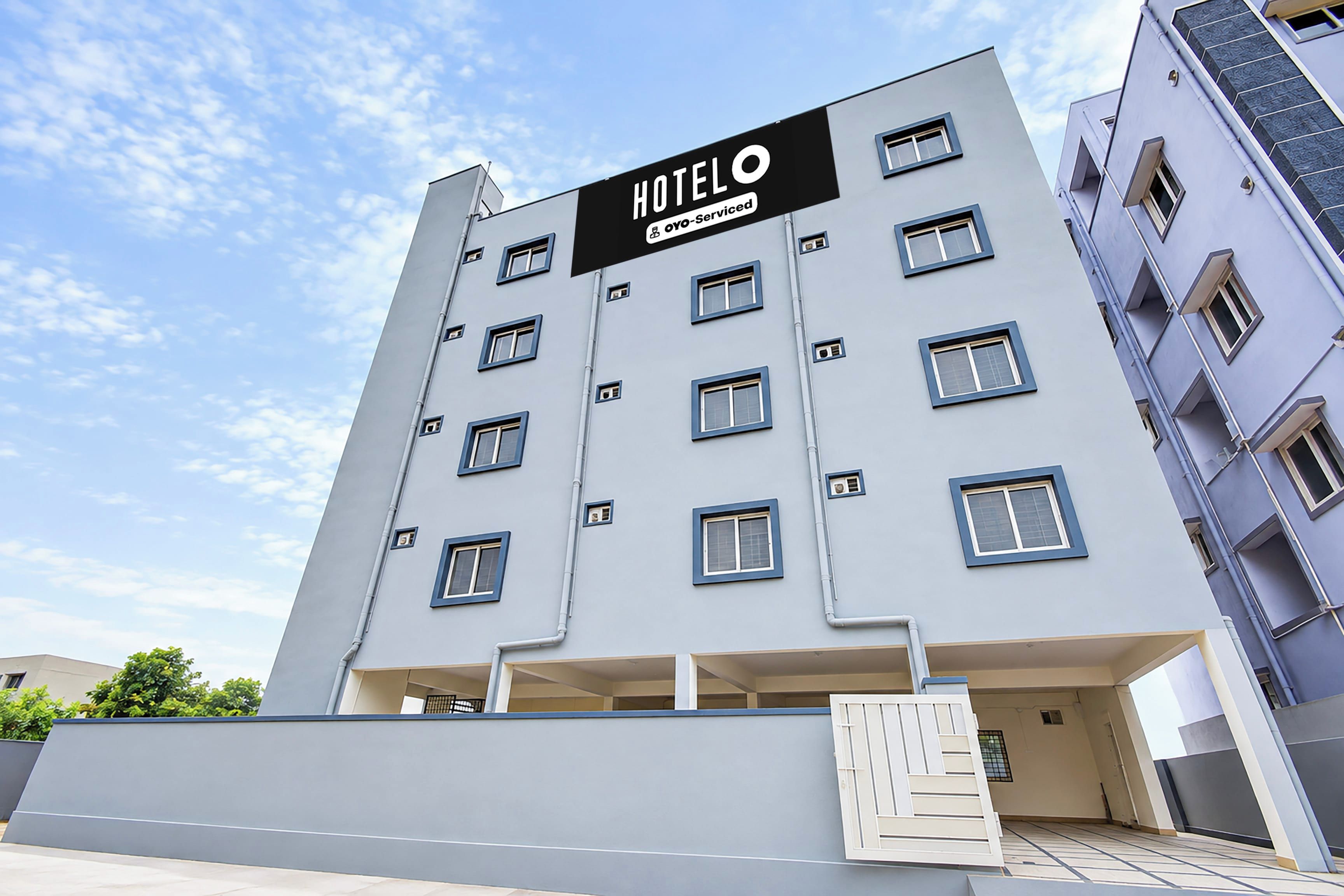 A modern hotel building with a sign indicating it is 'HOTEL 5o-Serviced'.