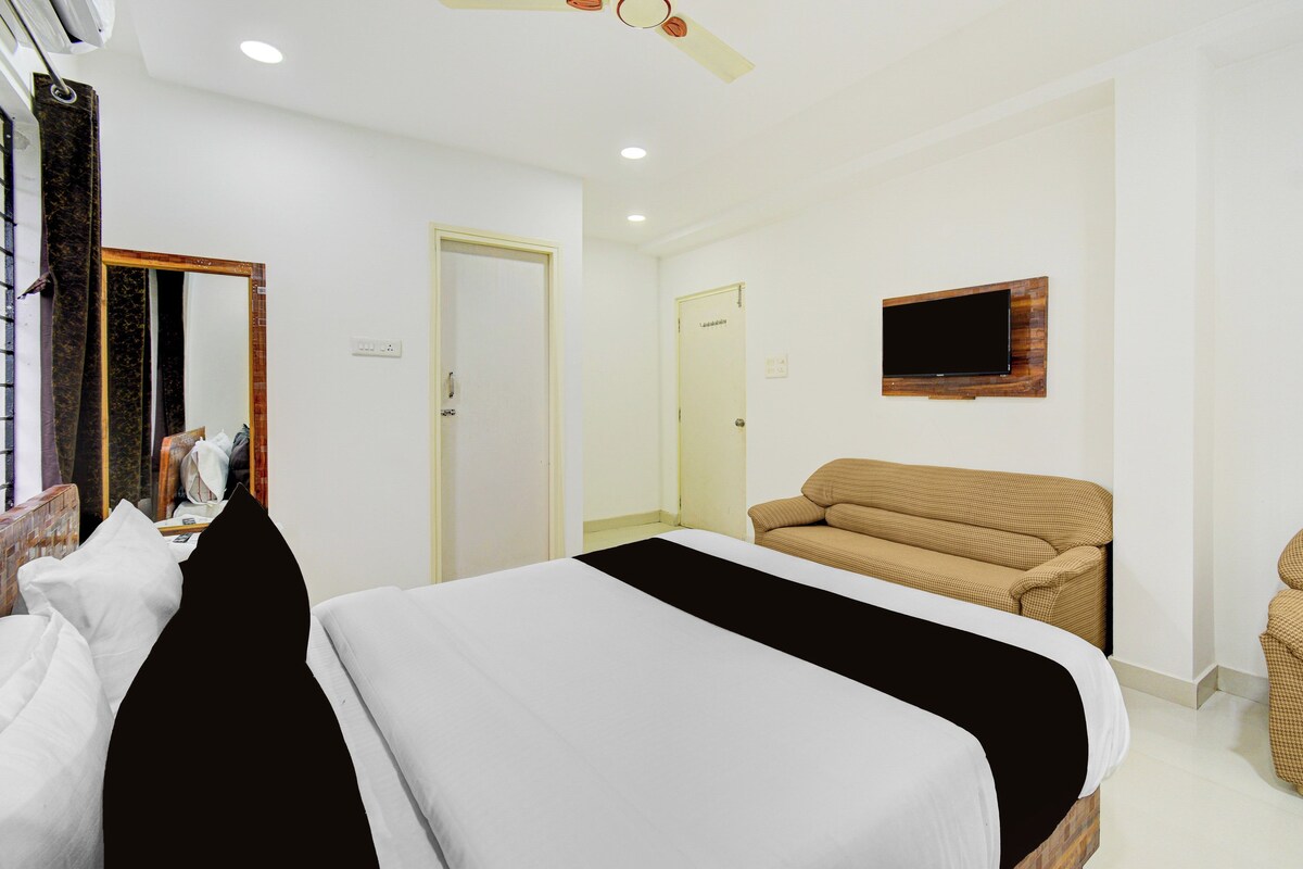 Una habitación de hotel con cama, sofá, televisión montada en la pared y ventilador de techo.