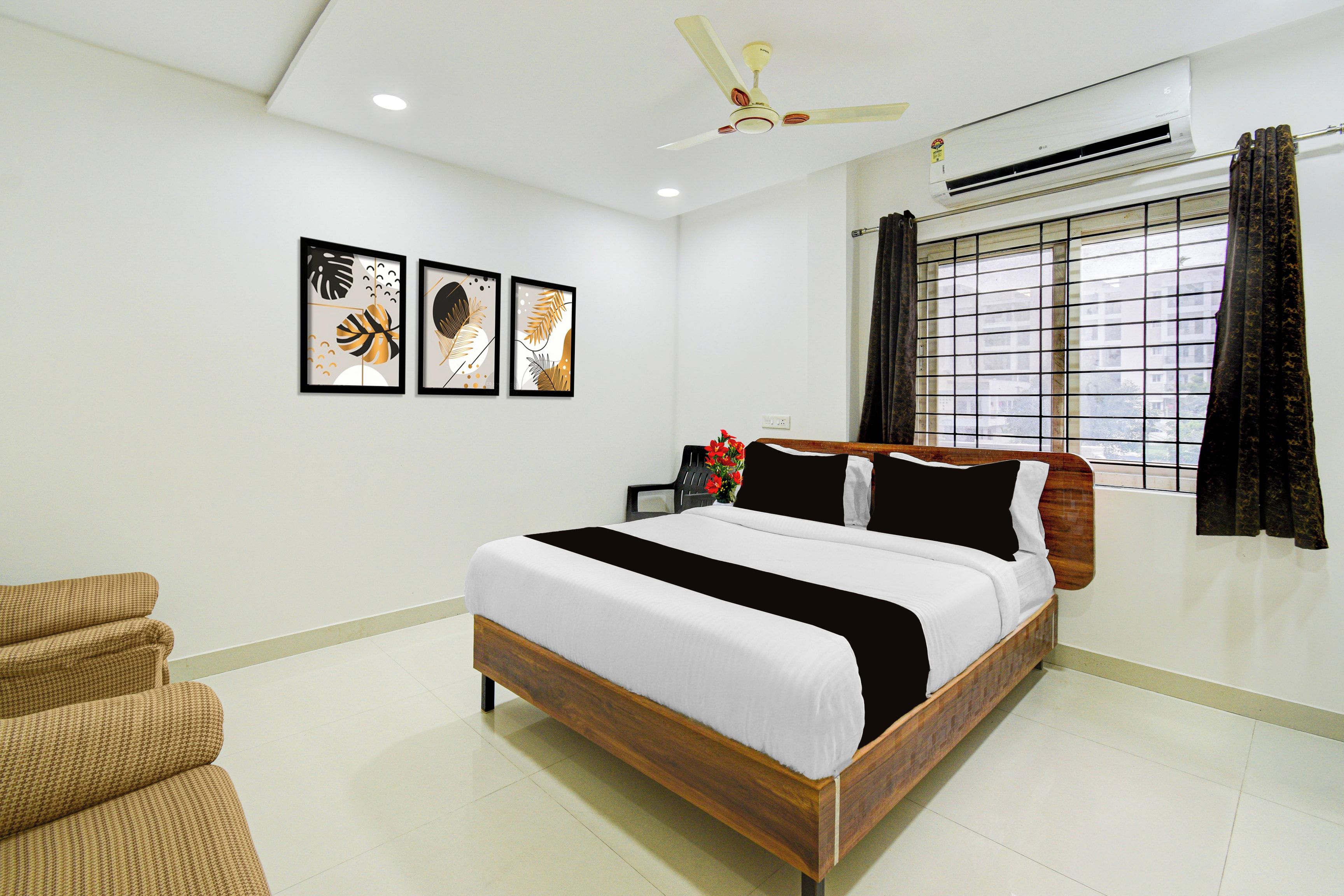 A bedroom with a bed, a chair, a ceiling fan, and framed artwork on the wall.