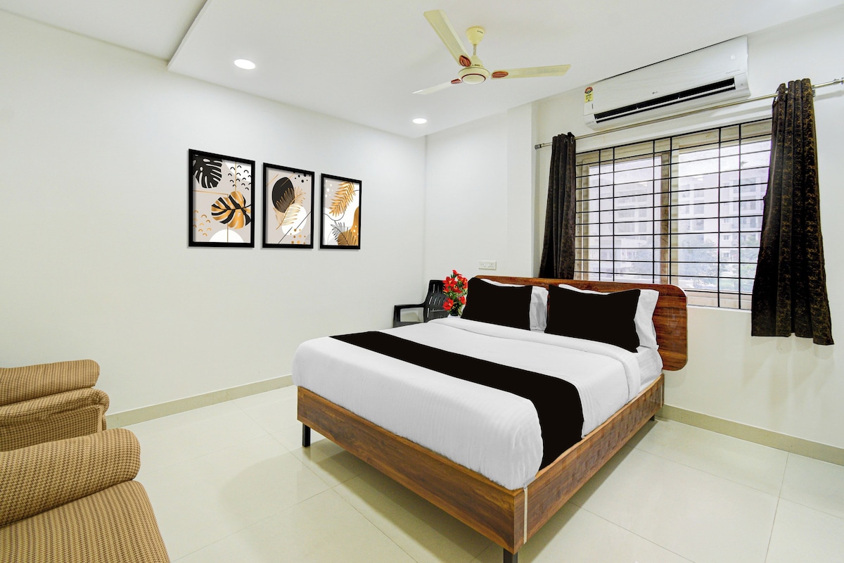 A bedroom with a bed, a chair, a ceiling fan, and framed artwork on the wall.