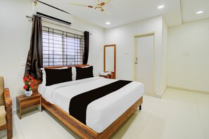 A bedroom with a bed, a nightstand, a mirror, a window with curtains, and a ceiling fan.