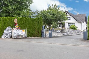 A residential area with a gated entrance, a well-maintained hedge, and a house with a sloped roof. - Room 'Doppelzimmer 10' with Shared Garden and Wi-Fi (Stadtallendorf)