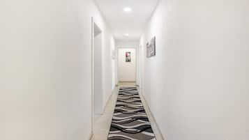 Ein Flur mit einem zebraartig gemusterten Teppich, weißen Wänden und einer Tür am Ende.