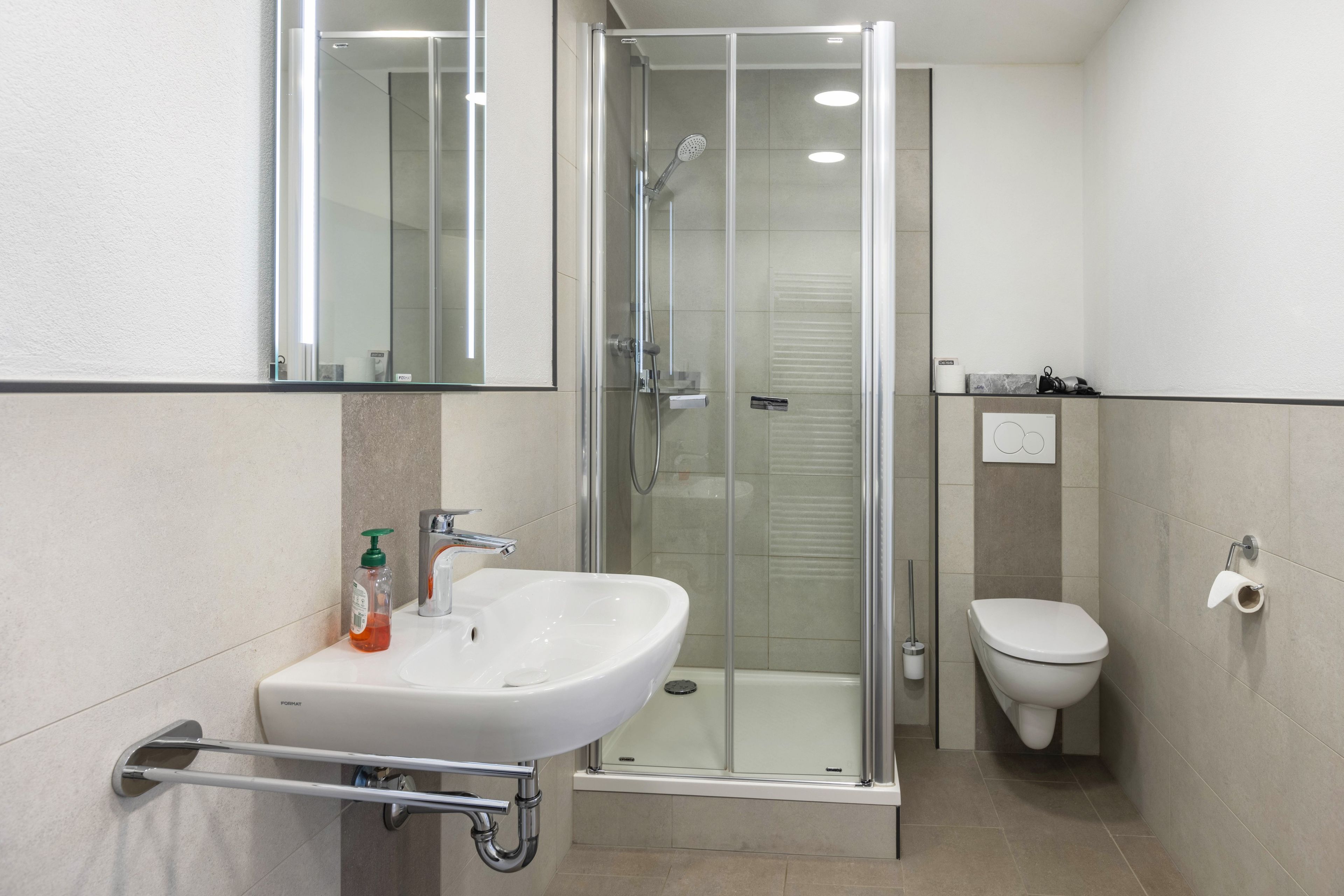 A modern bathroom with a glass-enclosed shower, a white sink, and a toilet.